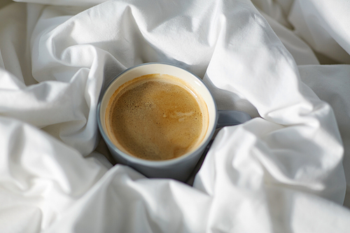 morning, hygge and drink concept - cup of coffee in bed at home