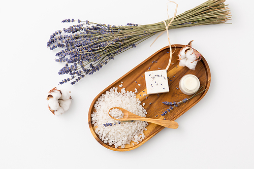 beauty and wellness concept - 씨솔트 with spoon, soap, moisturizer, lavender and cotton flowers on wooden tray