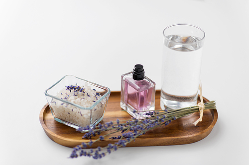 beauty and wellness concept - 씨솔트, perfume, lavender and glass of water on wooden tray