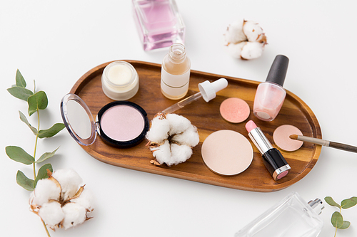beauty, natural cosmetics and make up products concept - makeup, perfume with cotton flower on wooden tray and eucalyptus cinerea