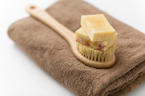 beauty, spa and wellness concept - close up of crafted soap bars and natural bristle wooden brush on bath towel