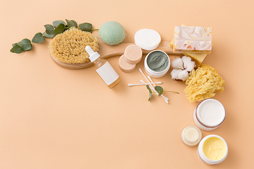 beauty, spa and wellness concept - close up of crafted soap bars, natural bristle wooden brush, body butter with sponge and serum on beige background