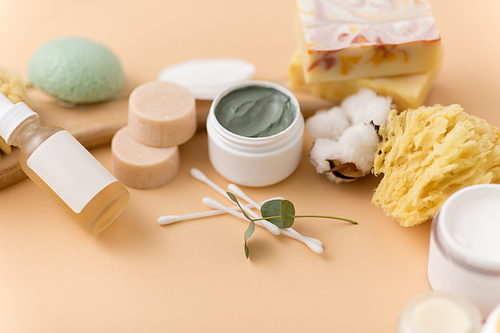 beauty, spa and wellness concept - close up of crafted soap bars, natural bristle wooden brush, body butter with sponge and herbs on beige background