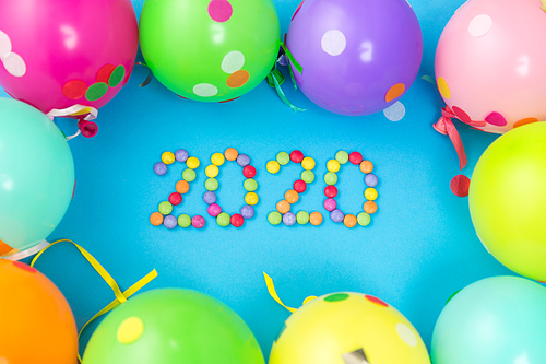 holidays, celebration and decoration concept - 2020 new year party date with colorful balloons on blue background