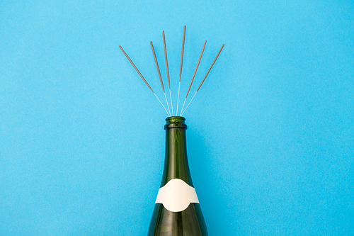 celebration, party and holidays concept - champagne bottle with sparklers on blue background