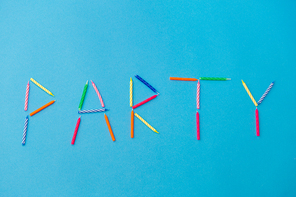 celebration, holiday and lettering concept - word party made of colorful birthday candles on blue background