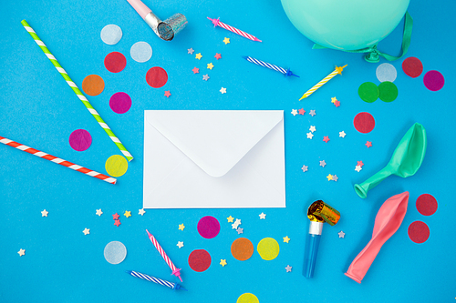 celebration and decoration concept - white postal envelope birthday party props and colorful confetti on blue background
