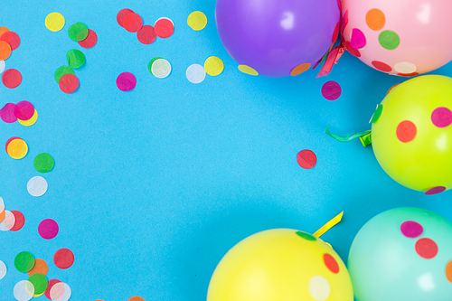 party props, celebration and decoration concept - colorful balloons and confetti on blue background