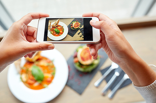 food, eating, technology, culinary and people concept - woman hands with smartphone photographing gazpacho soup and salad at restaurant