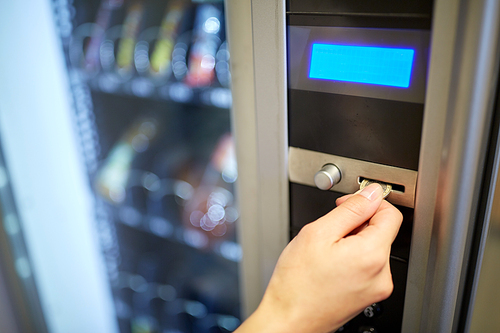 sell, technology, people, finances and consumption concept - hand inserting euro coin to vending machine money slot