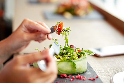 food, culinary, haute cuisine and people concept - woman eating cottage cheese salad with vegetables and dried raspberries at restaurant or cafe