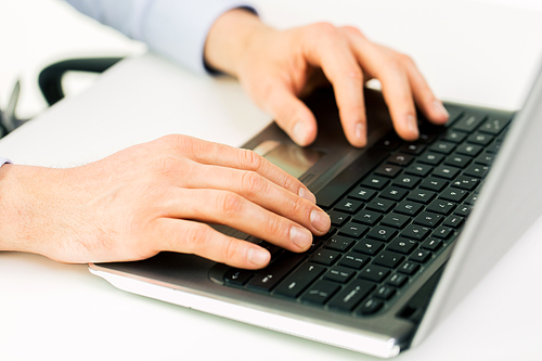 business, education, people and technology concept - close up of male hands with laptop on table typing