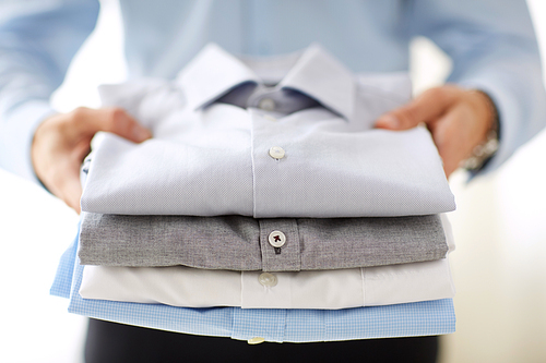 business, clothes, formal wear and people concept - close up of businessman holding shirts