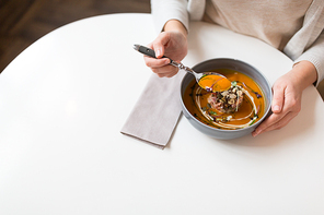 food, new nordic cuisine and people concept - woman eating vegetable pumpkin-ginger cream soup with goat cheese and tomato salad with yogurt in bowl at cafe or restaurant