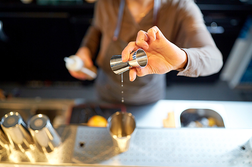 alcohol drinks, people and luxury concept - woman bartender with jigger pouring syrup into shaker and preparing cocktail at bar counter