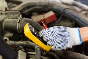 car service, repair, maintenance and people concept - auto mechanic man with digital multimeter testing battery at workshop