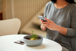 food, new nordic cuisine, technology, eating and people concept - woman sitting at cafe table with smartphone and bowl of soup