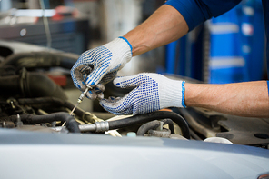 car service, repair, maintenance and people concept - auto mechanic man with dipstick and lamp checking for motor oil level at workshop