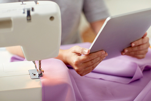 people, needlework, technology and tailoring concept - tailor woman with sewing machine, tablet pc and fabric