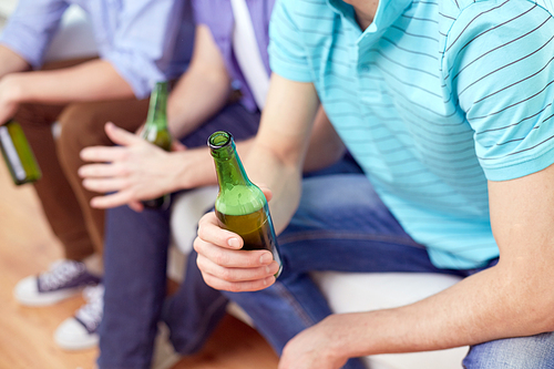 alcohol and people concept - men with beer bottles sitting on sofa at home
