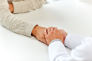 medicine, age, support, healthcare and people concept - close up of doctor or nurse holding senior man hand at hospital