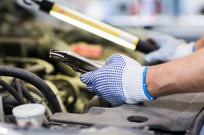 car service, repair, maintenance and people concept - auto mechanic man with lamp and pliers working at workshop