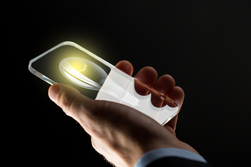 business, solution, idea, people and future technology concept - close up of businessman hand with lightbulb on transparent smartphone screen over black background