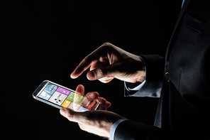 business, multimedia, people and future technology concept - close up of businessman hands with transparent smartphone with applications over black background
