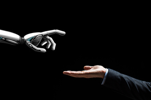 artificial intelligence, future technology and communication concept - robot and human hand on black background