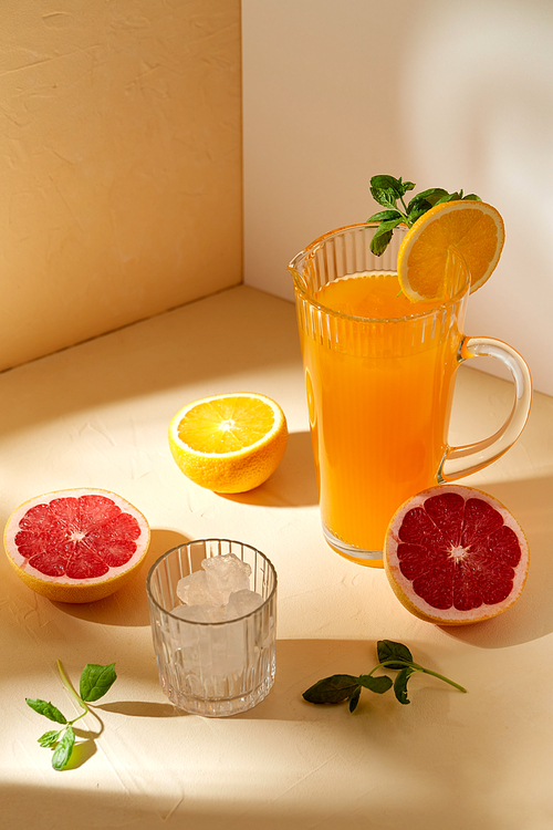 drink, detox and diet concept - jug with orange juice, cut grapefruit and ice cubes in glass on table
