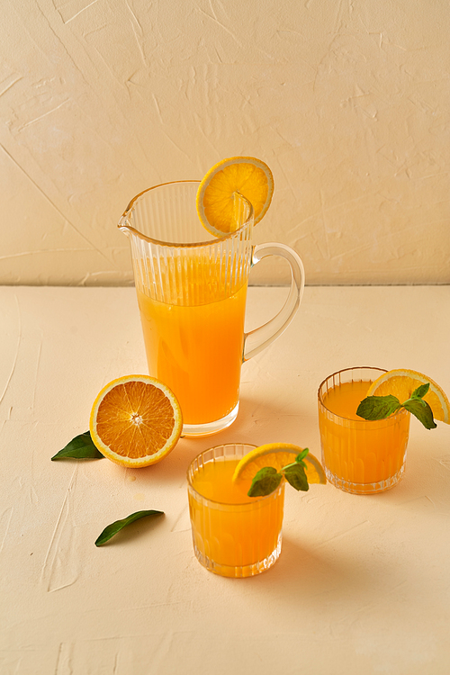 drink, detox and diet concept - glasses with fruit orange juice and peppermint on table