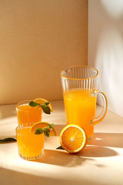 drink, detox and diet concept - glasses with fruit orange juice and peppermint on table