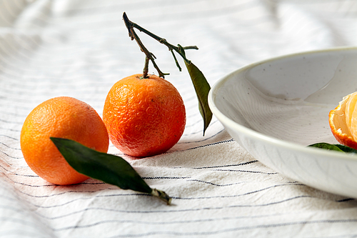 food, healthy eating and fruits concept - close up of mandarins on plate over drapery