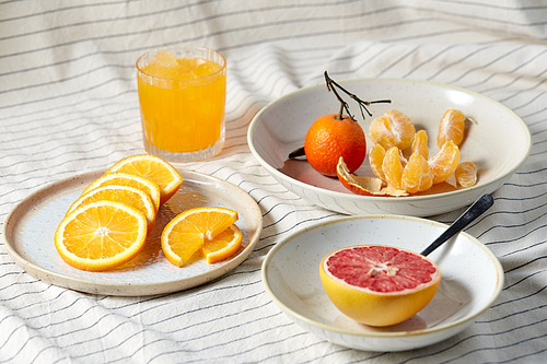 food, healthy eating and fruits concept - still life of mandarin, grapefruit and glass of orange juice over drapery