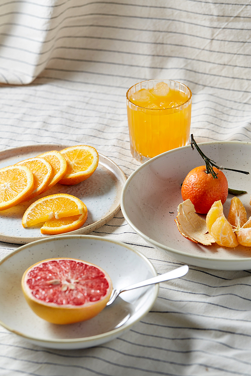 food, healthy eating and fruits concept - still life of mandarin, grapefruit and glass of orange juice over drapery