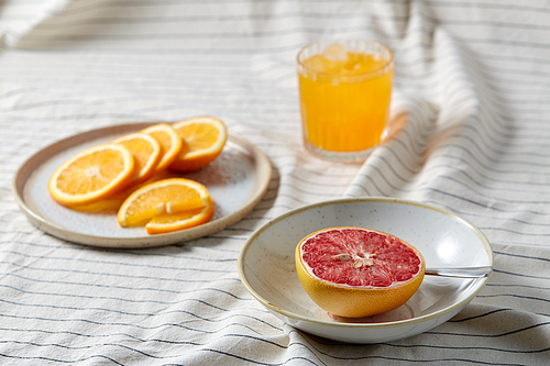 food, healthy eating and fruits concept - still life of grapefruit, sliced orange and glass of juice over drapery