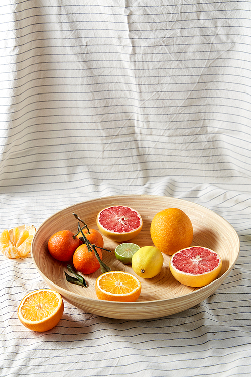 food, healthy eating and vegetarian concept - close up of citrus fruits on wooden plate