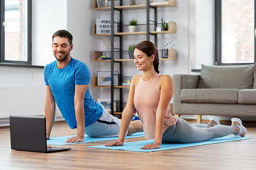 sport, fitness, lifestyle and people concept - smiling man and woman with laptop computer exercising at home