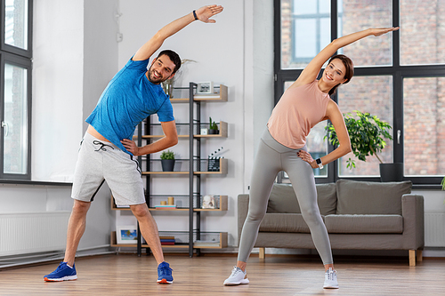 sport, fitness, lifestyle and people concept - smiling man and woman exercising at home