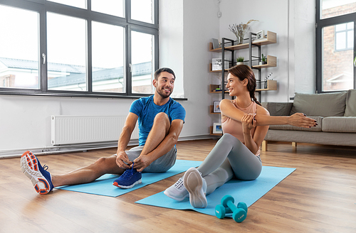 sport, fitness, lifestyle and people concept - smiling man tying laces and woman stretching at home