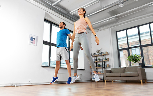 sport, fitness and healthy lifestyle concept - smiling man and woman exercising and jumping at home