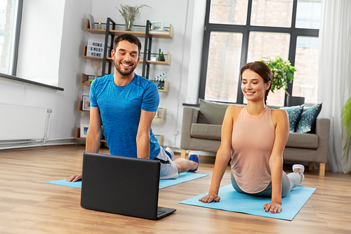 sport, fitness, lifestyle and people concept - smiling man and woman with laptop computer exercising at home