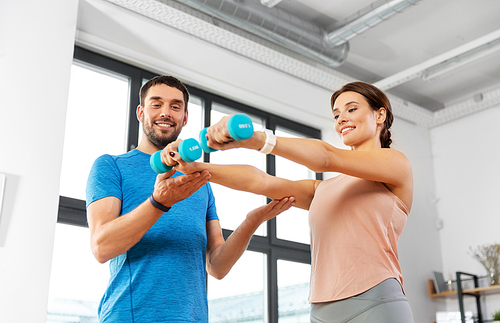 sport, fitness, lifestyle and people concept - smiling man and woman exercising with dumbbells at home
