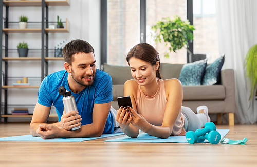 fitness, sport and technology concept - happy couple with smartphone having break at home