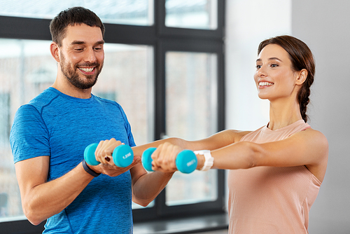 sport, fitness, lifestyle and people concept - smiling man and woman exercising with dumbbells at home