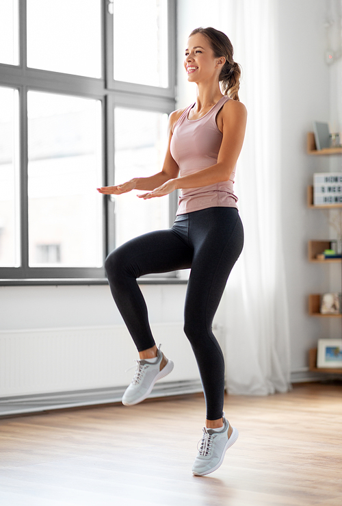 sport, fitness and healthy lifestyle concept - smiling young woman exercising and jumping at home