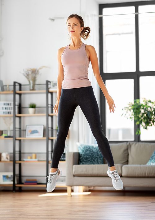 sport, fitness and healthy lifestyle concept - young woman exercising and jumping at home