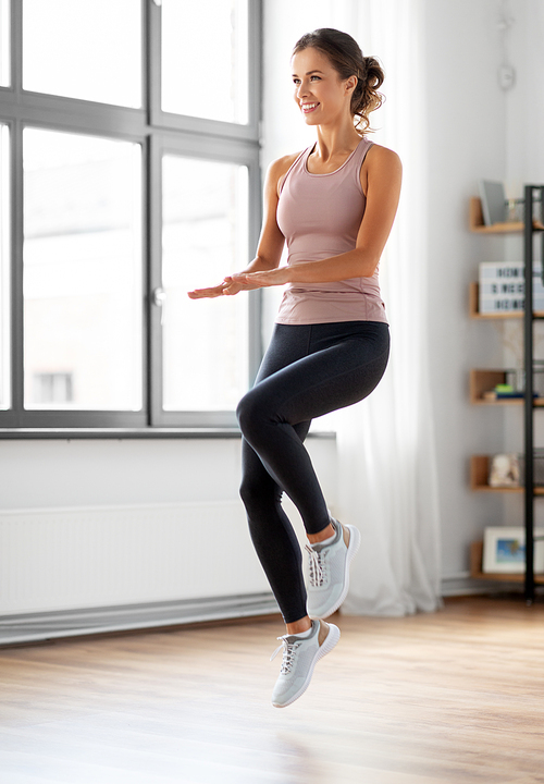 sport, fitness and healthy lifestyle concept - smiling young woman exercising and jumping at home