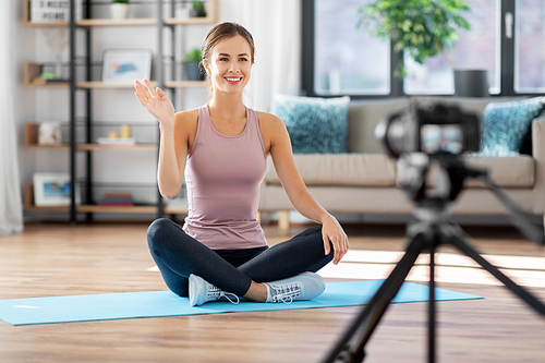 fitness, sport and video blogging concept - happy smiling woman or Vlog with camera streaming online yoga class at home