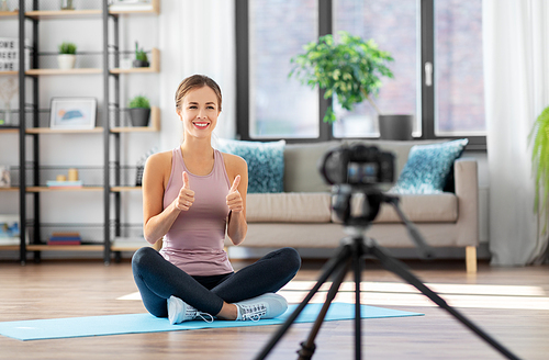 fitness, sport and video blogging concept - woman or Vlog with camera on tripod recording online training class at home